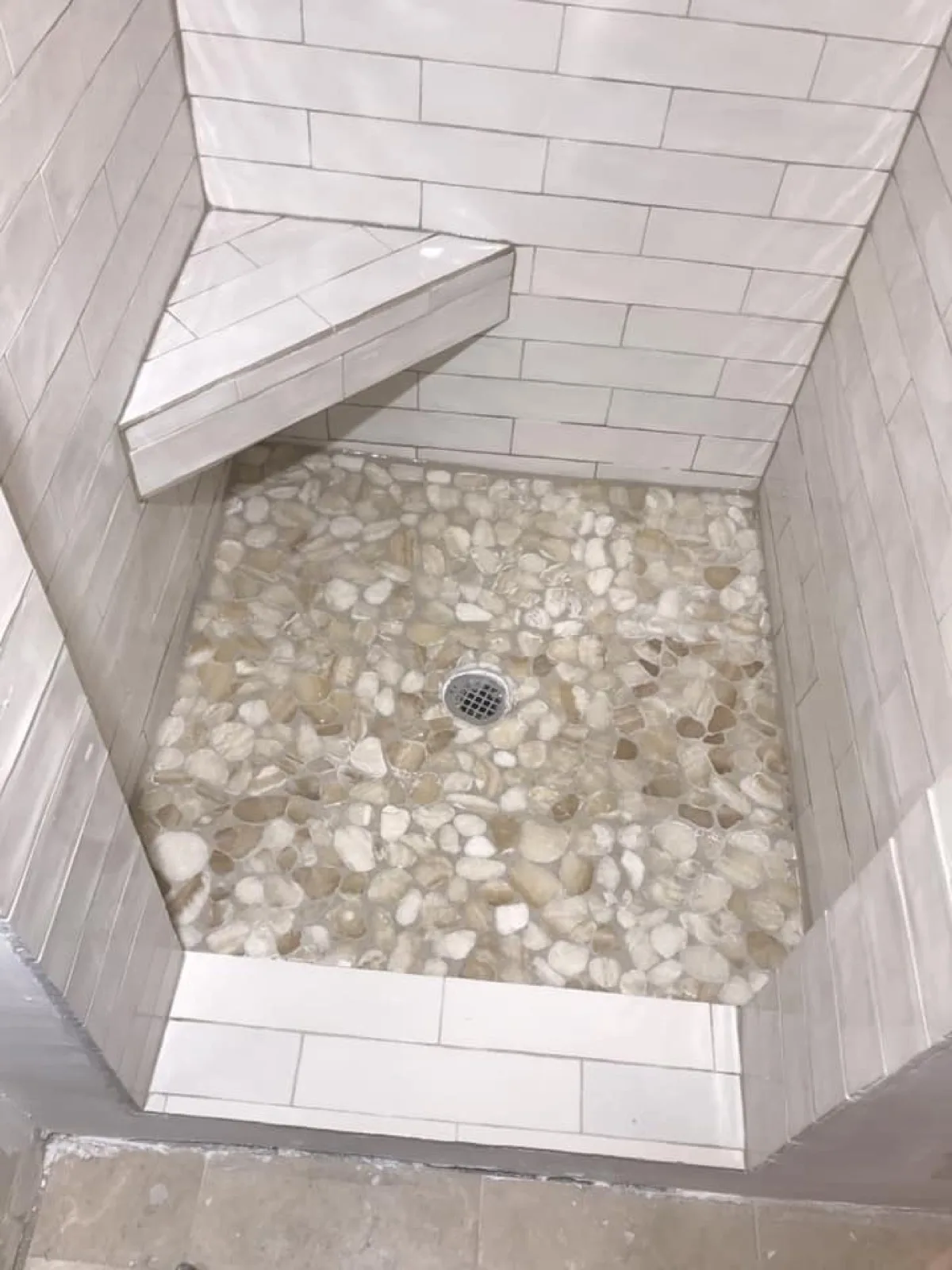 Pebble tile shower floor detail in a completed bathroom
